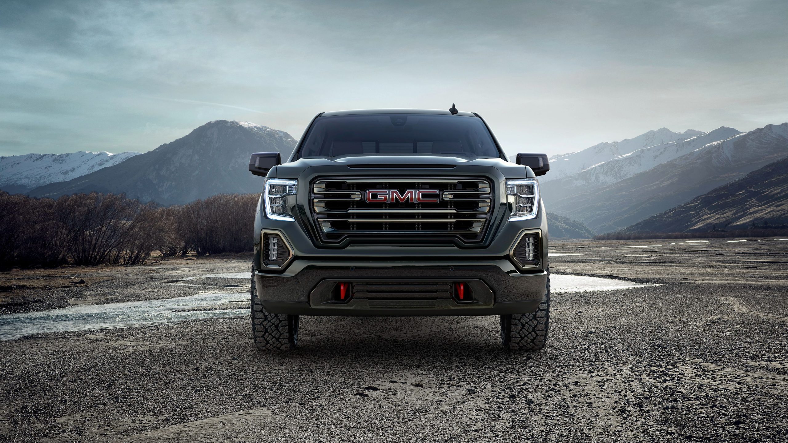 GMC pickup faces forward against a dramatic alpine backdrop, highlighting its rugged design and stance