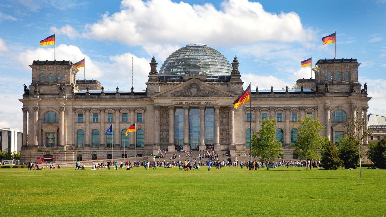 Germany’s Reichstag building in Berlin showcases its historic façade, glass dome, and national flags