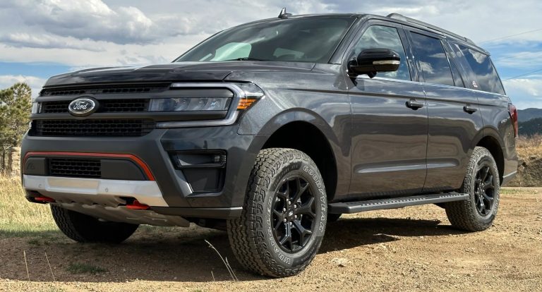 Gray Ford Expedition SUV parked on rugged terrain, showcasing its bold grille and off-road styling