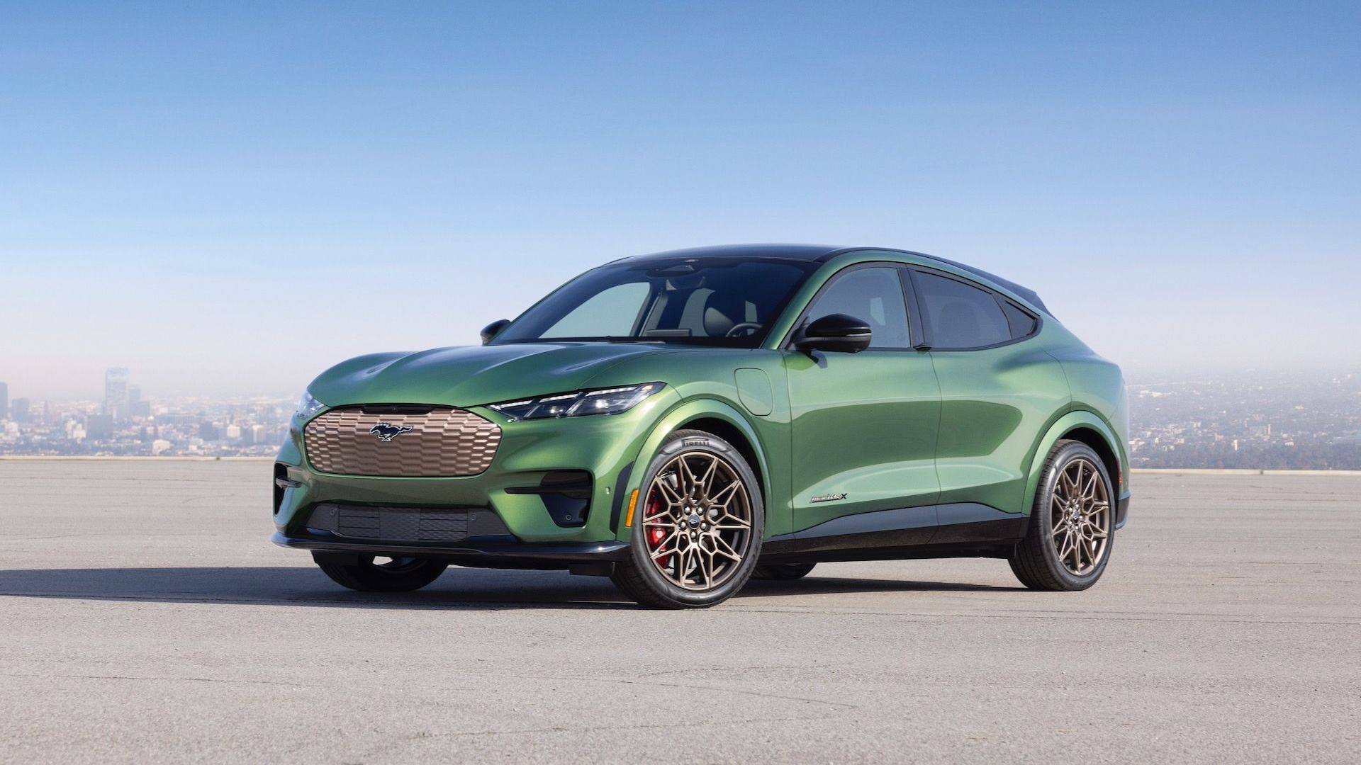 Green Ford Mustang Mach-E GT parked against a city skyline, highlighting its sporty all-electric crossover design