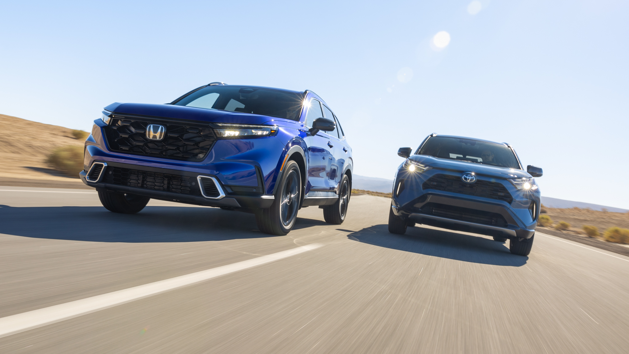 Honda CR-V Hybrid and Toyota RAV4 Hybrid drive side by side on a sunlit highway
