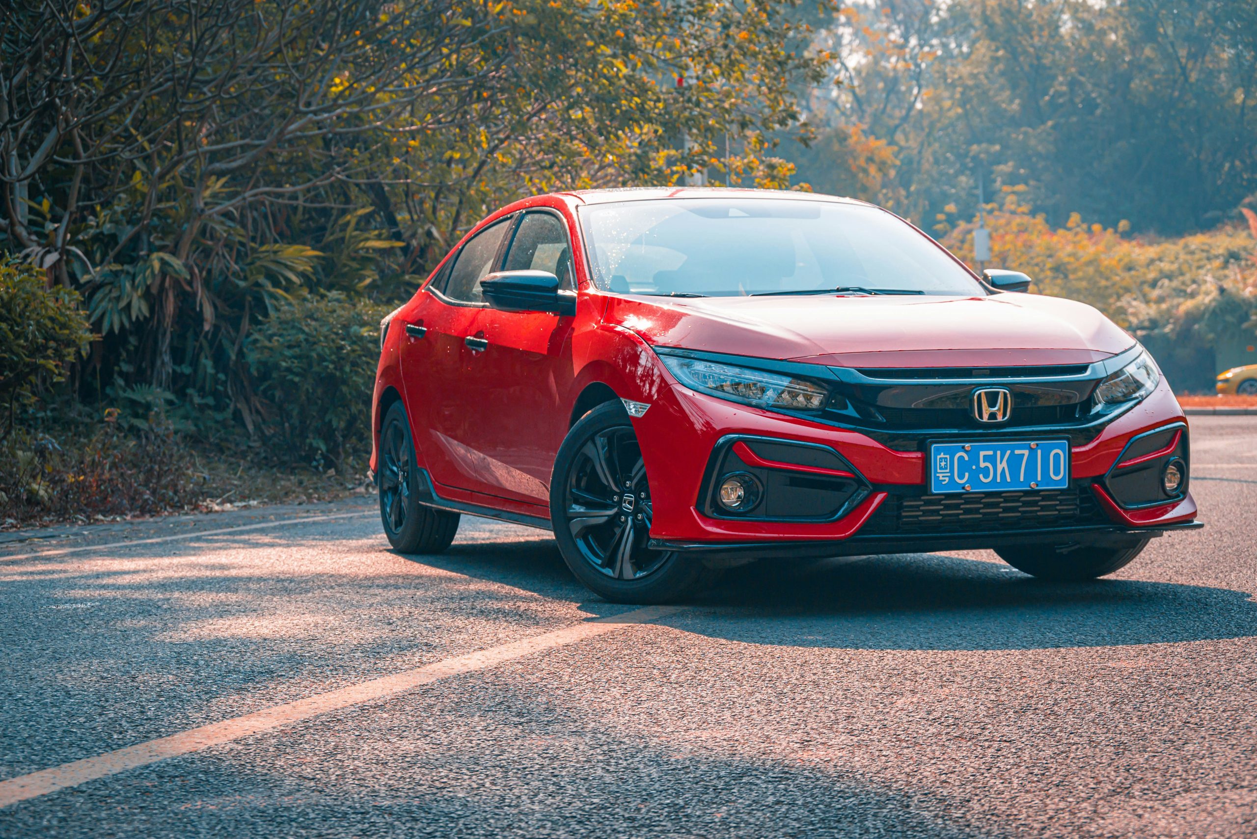 A red Civic is standing on a road on a sunny day
