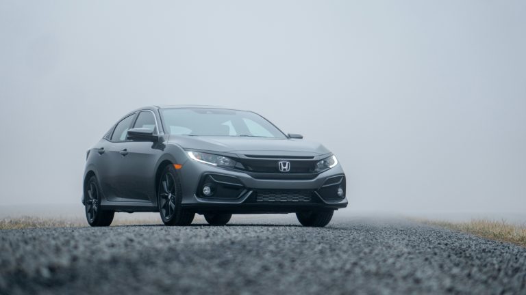 A Civic is stanindg on a misty day on a concrete road