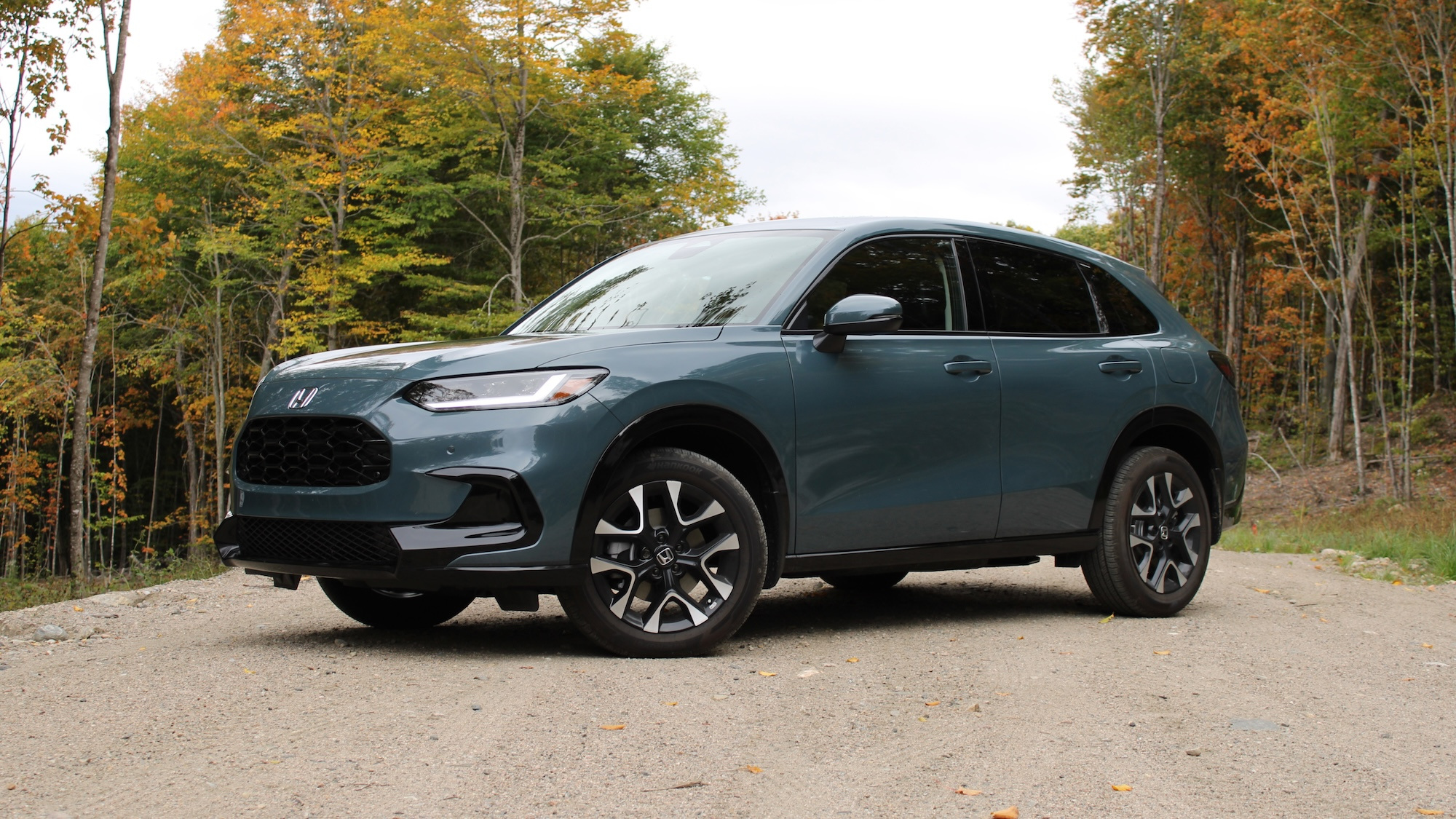 Honda HR-V EX-L parked beside an autumn forest, showcasing its modern compact SUV design