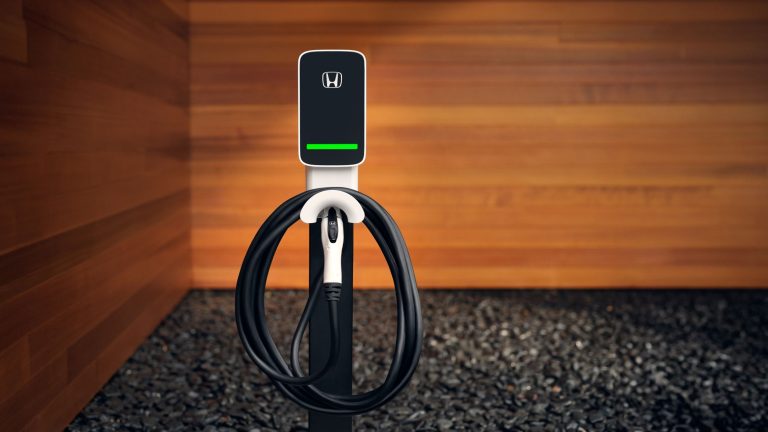 Honda electric vehicle wall charger mounted against a wooden wall in a modern garage