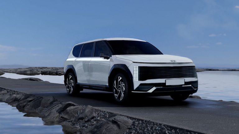 Hyundai Ioniq 7 electric SUV drives along a rugged coastal road beside rocky shores