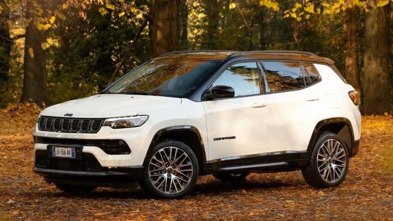 Jeep Compass parked among autumn trees on a leaf-covered forest trail