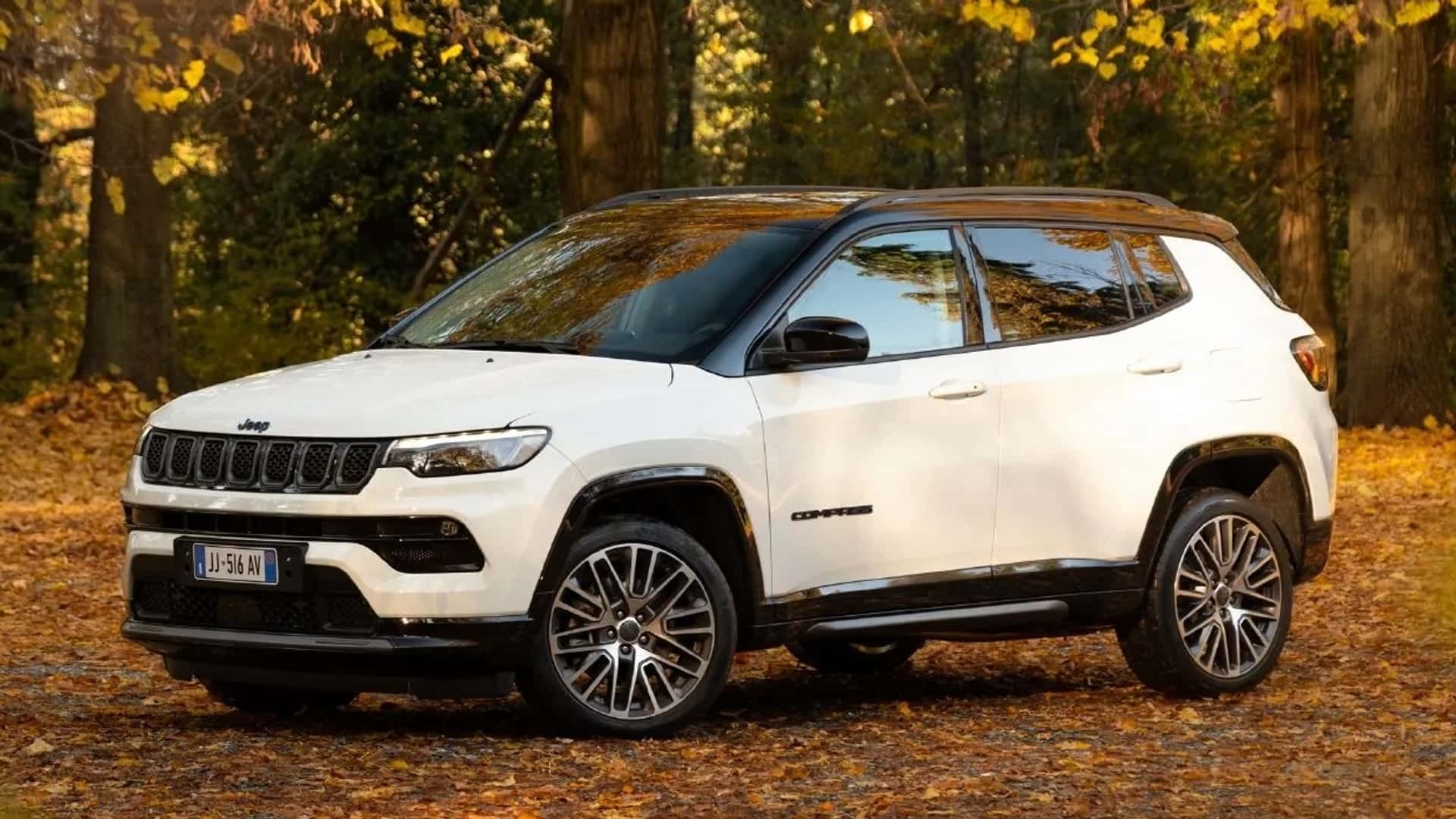 Jeep Compass parked among autumn trees on a leaf-covered forest trail