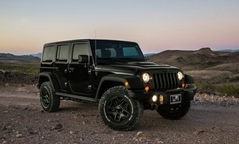 A black Wrangler is standing on a deserted road