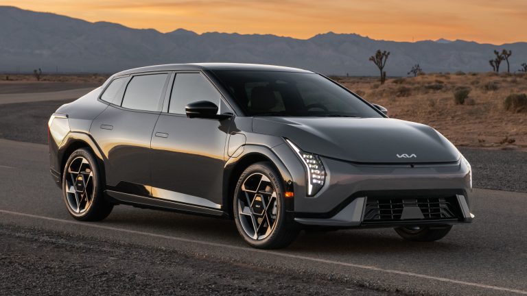 Kia EV4 sedan parked on a desert road with mountains beneath a sunset sky