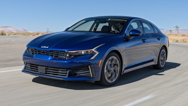 Kia K5 cruising along an open highway, showcasing its sleek styling and modern sedan design