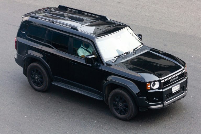 A black Land Cruiser is standing on a road