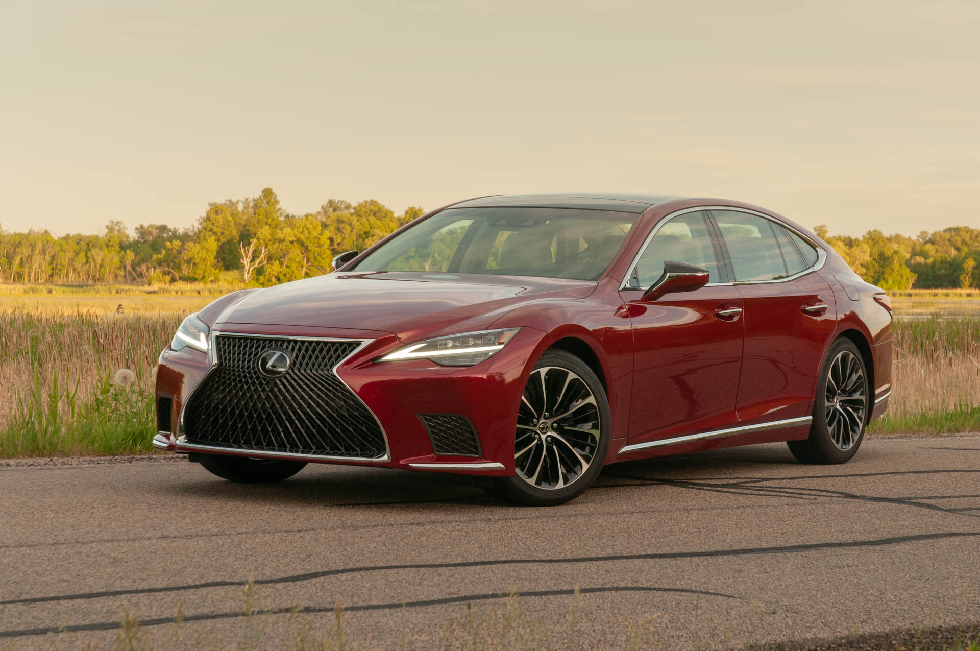 A maroon Lexus is standing on a road