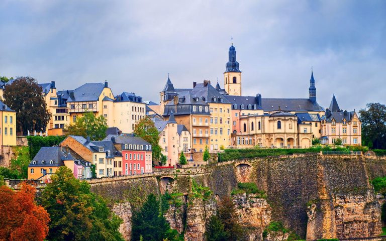 Luxembourg’s historic Old Town features colorful buildings perched above dramatic stone cliffs