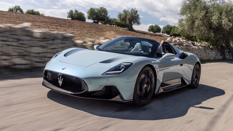 Maserati MC20 convertible speeds along a scenic road, showcasing its sleek design and performance