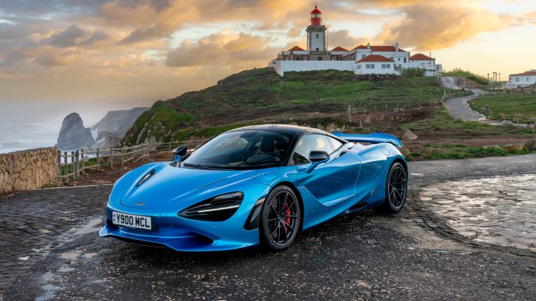 McLaren 750S parked near a coastal lighthouse on a scenic mountain road