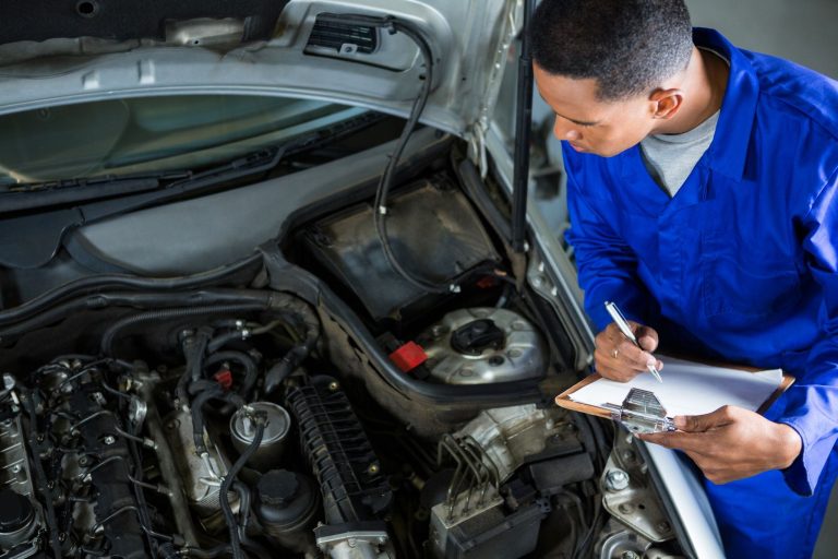 Mechanic inspects an open car engine and records maintenance details on a clipboard