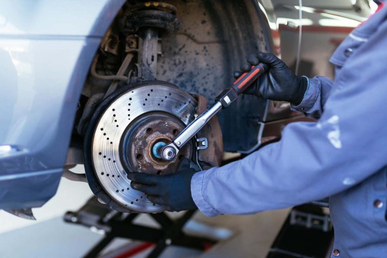 Mechanic tightens a car’s wheel assembly with a torque wrench during brake maintenance