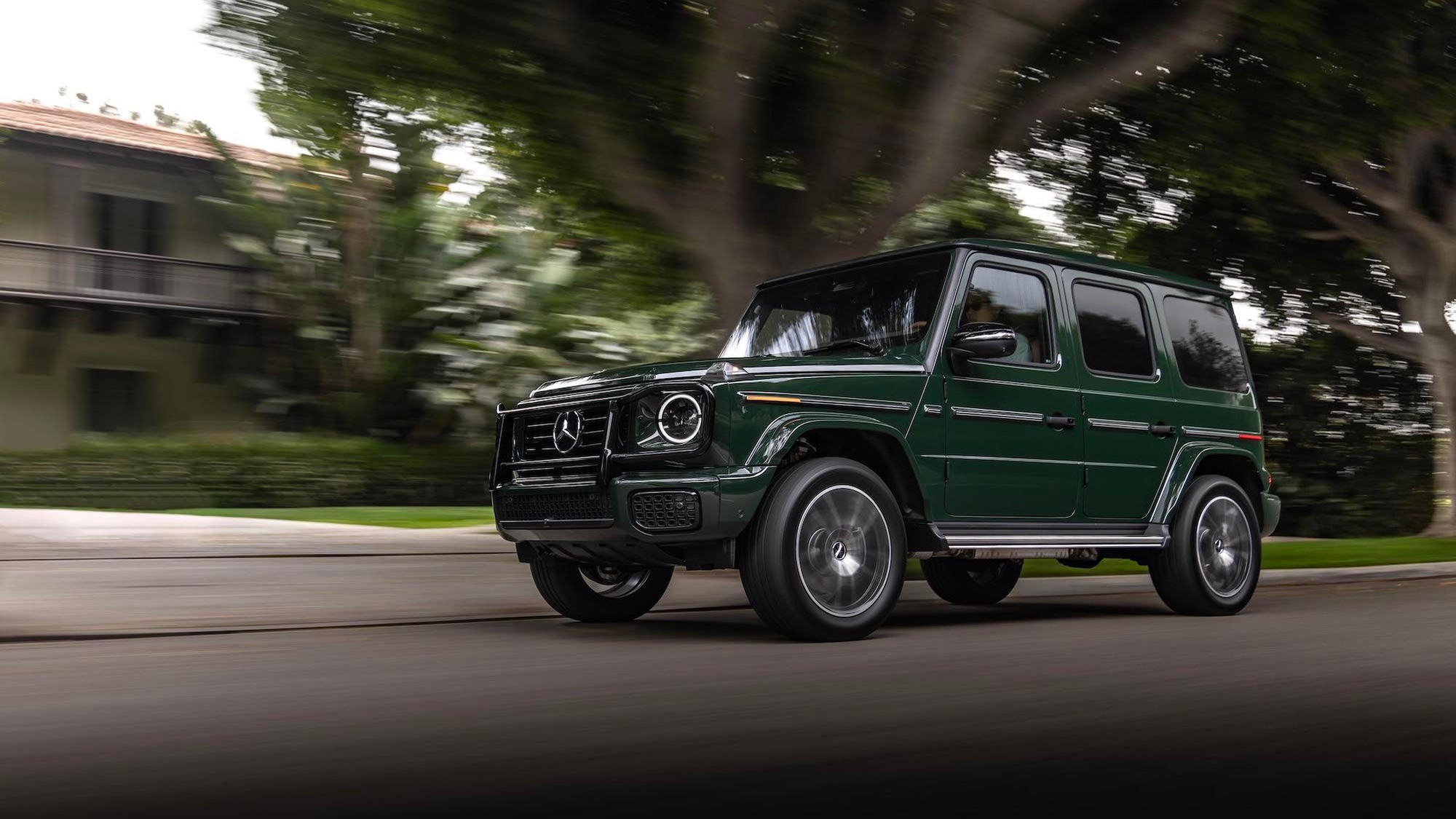 Mercedes-Benz G-Class cruises through a tree-lined neighborhood, showcasing its iconic boxy design and luxury appeal