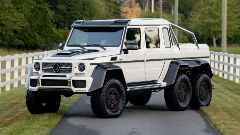 Mercedes-Benz G63 AMG 6x6 parked on a quiet road beside lush greenery