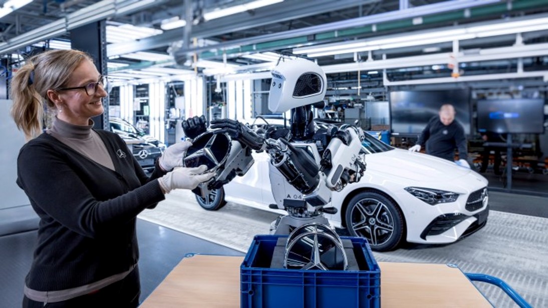 Mercedes-Benz humanoid robot assisting with steering wheel assembly inside an automotive factory, showcasing manufacturing automation