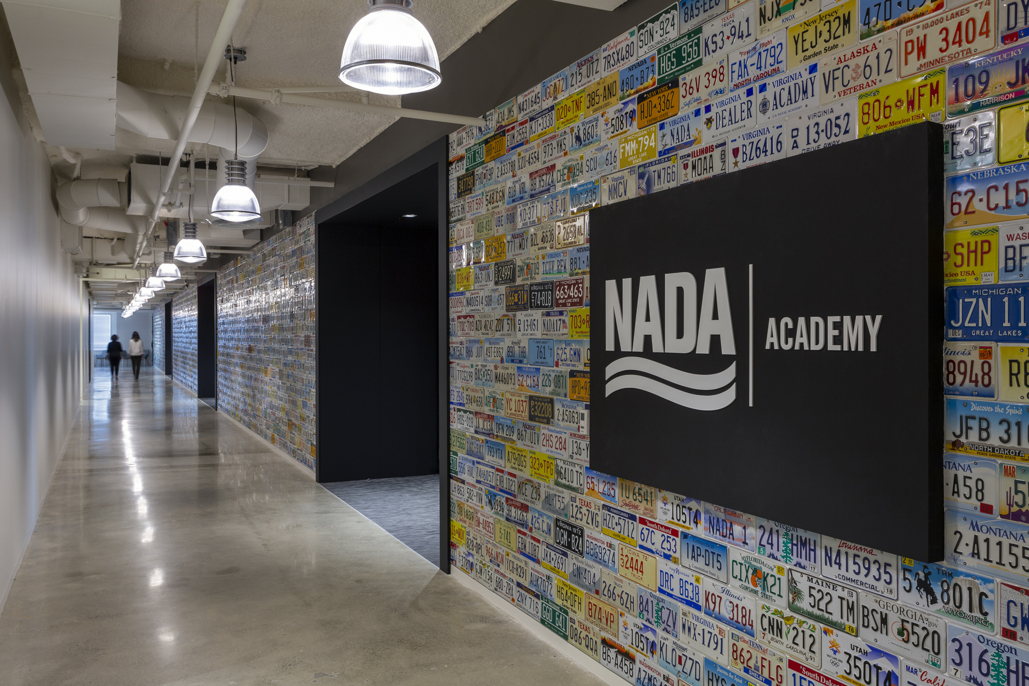 NADA Academy hallway features colorful license plates covering walls beside a prominent entrance sign