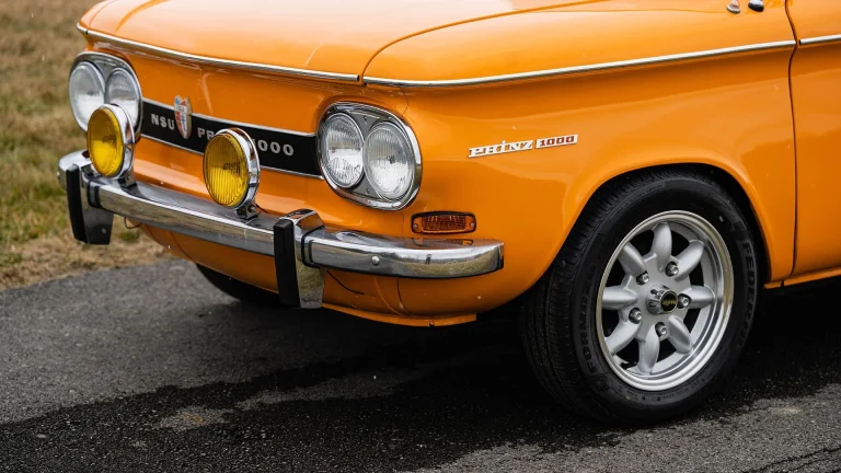 An Orange NSU is standing is standing on the road with a closup image of the front portion