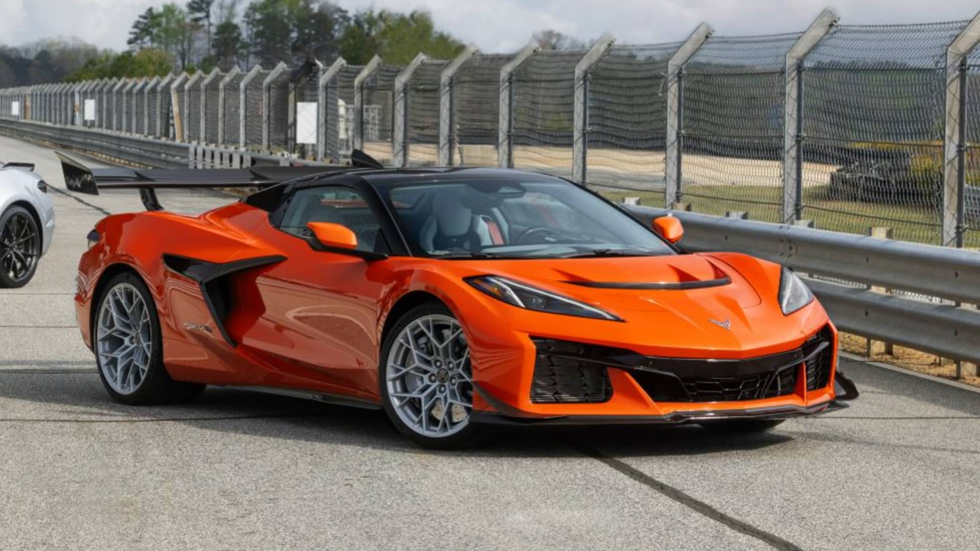 Orange Chevrolet Corvette ZR1X parked on a racetrack, showcasing its aggressive styling and prominent rear wing