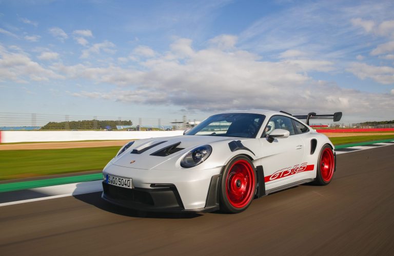 Porsche 911 GT3 RS speeding around a racetrack, showcasing aerodynamic styling and performance