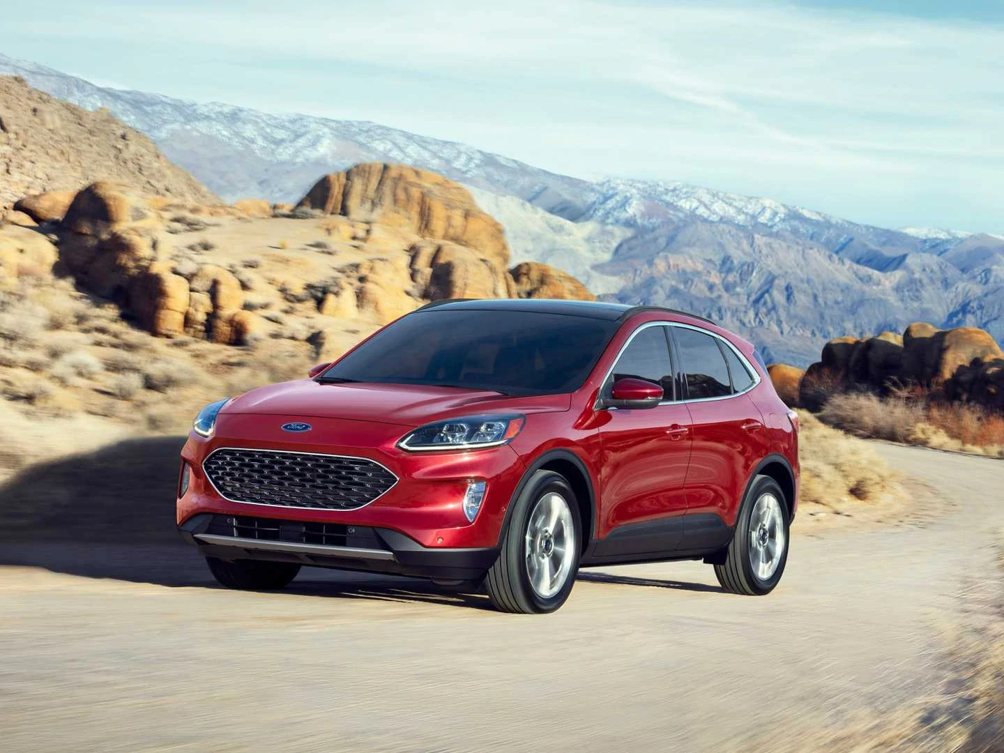 Red Ford Escape Hybrid driving through a scenic desert mountain road in bright daylight