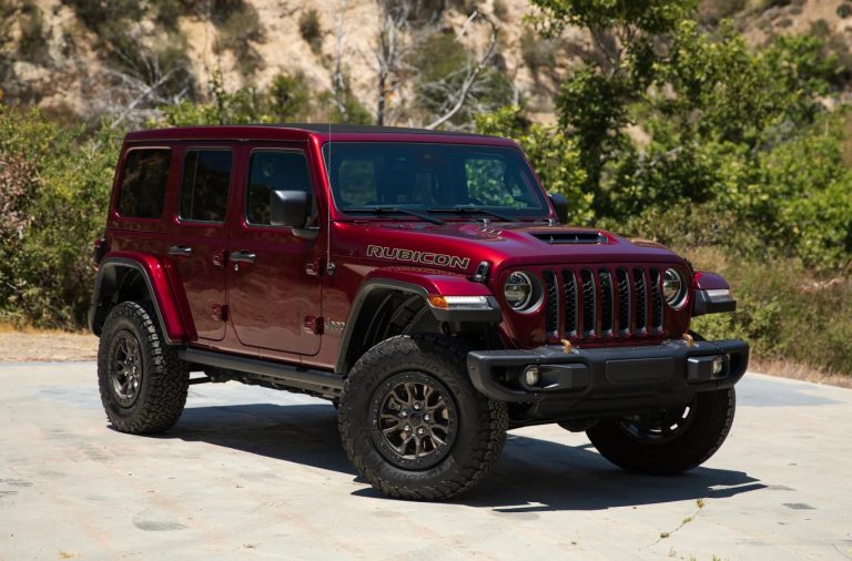 Red Jeep Wrangler Rubicon parked outdoors, showcasing its rugged off-road tires, iconic grille, and trail-ready design