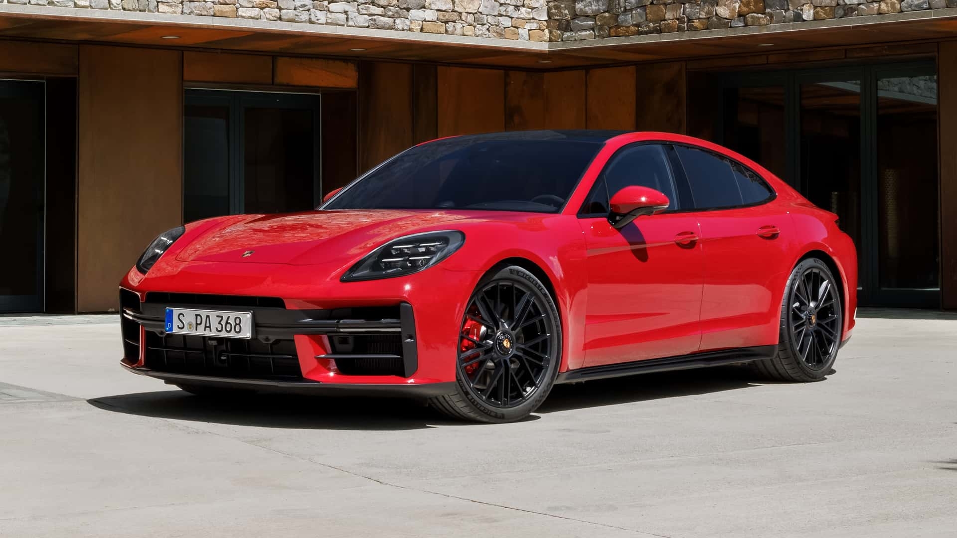 Red Porsche Panamera parked outside a modern residence, showcasing its sleek luxury sedan styling