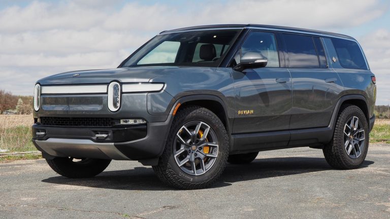 Rivian R1S SUV parked outdoors on pavement beneath a partly cloudy sky
