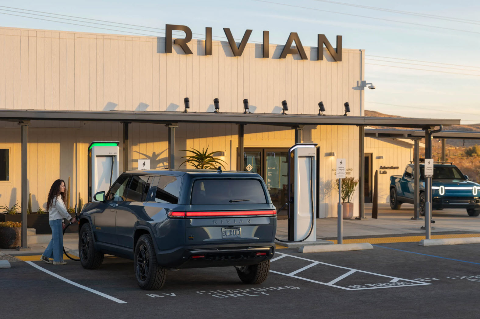 Rivian electric pickup charging outside the company’s facility, highlighting its EV infrastructure and adventure-focused lineup