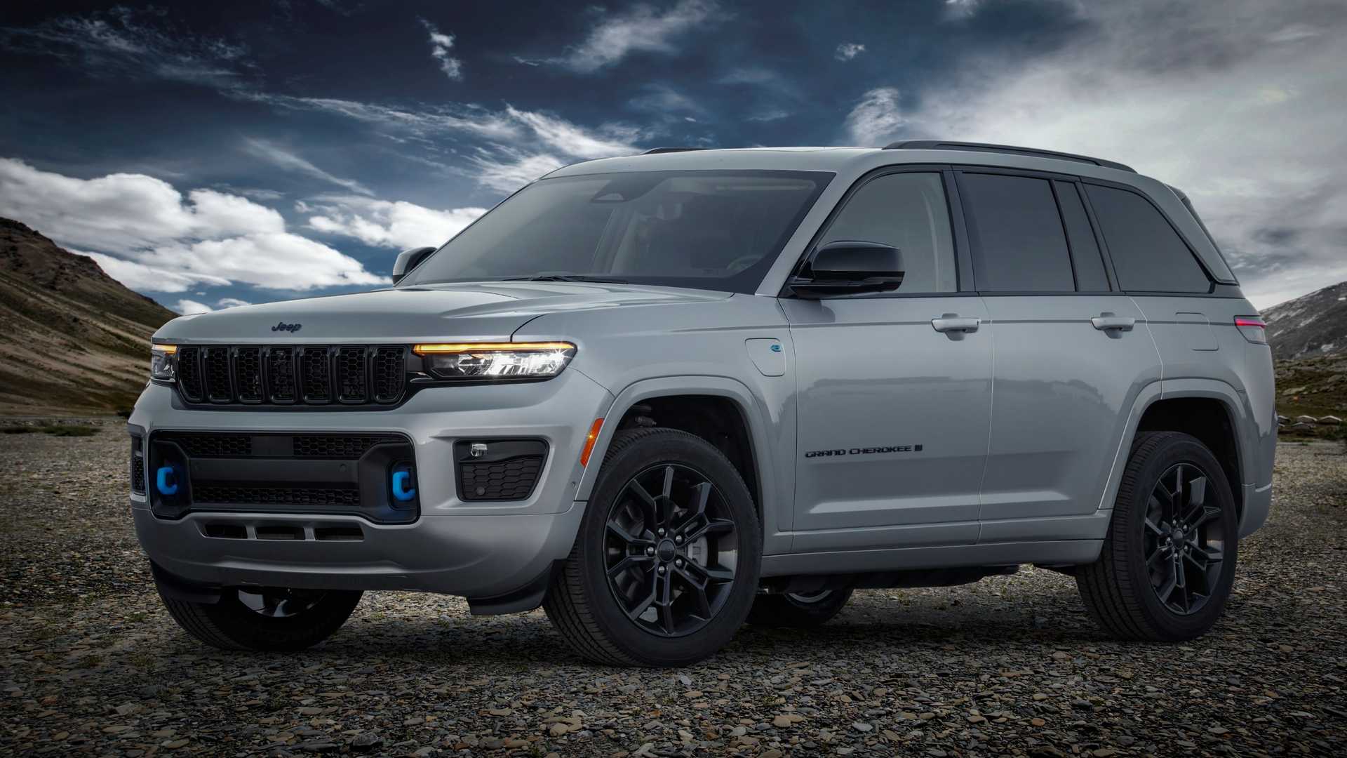 Silver Jeep Grand Cherokee 4xe parked on rocky terrain beneath dramatic skies, highlighting its rugged styling