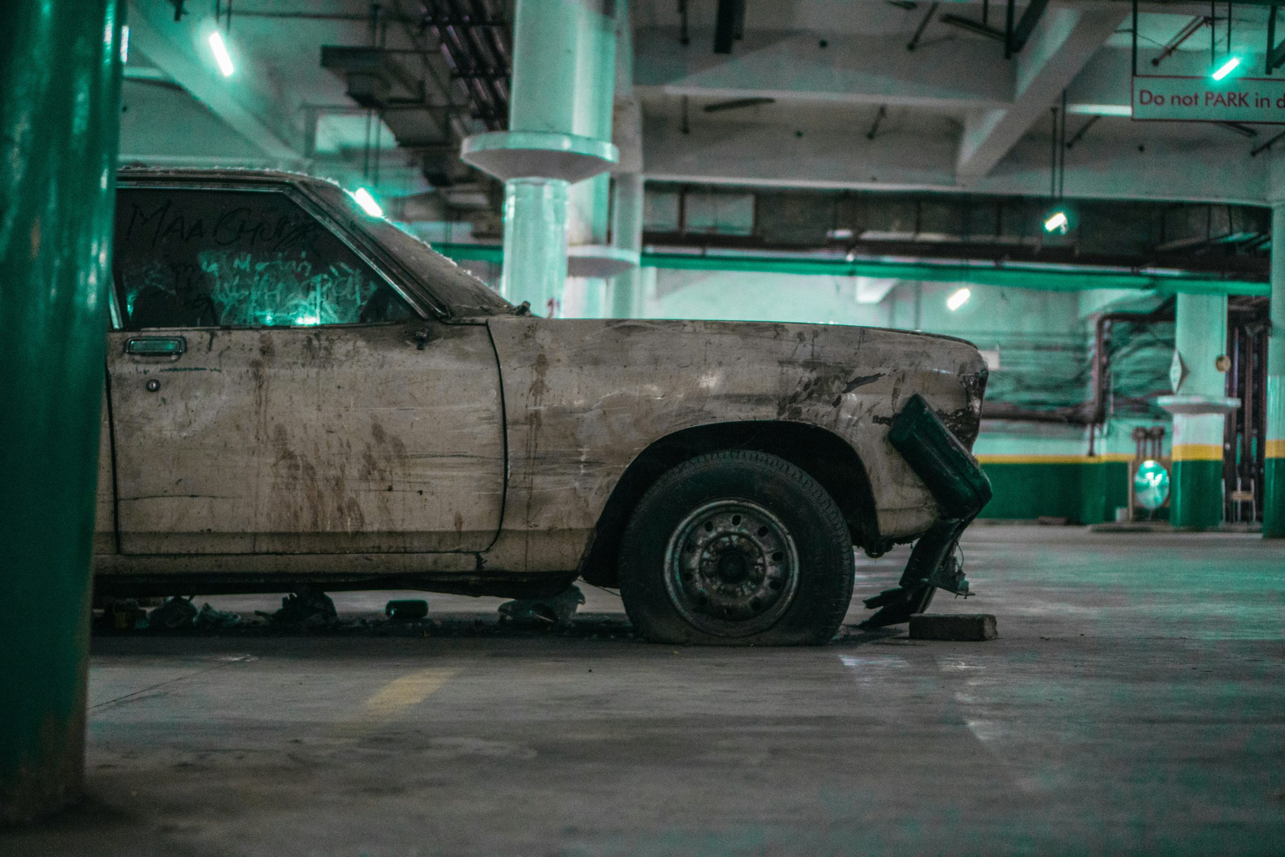 A damaged old car is standing in a parking lot