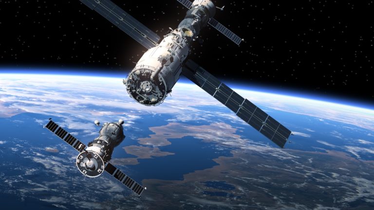 Space satellites orbiting above Earth, with the planet’s horizon visible beneath them