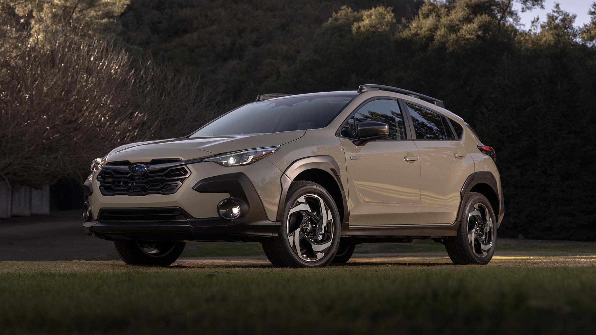 Subaru Crosstrek Hybrid parked on grass at dusk, showcasing its rugged crossover styling