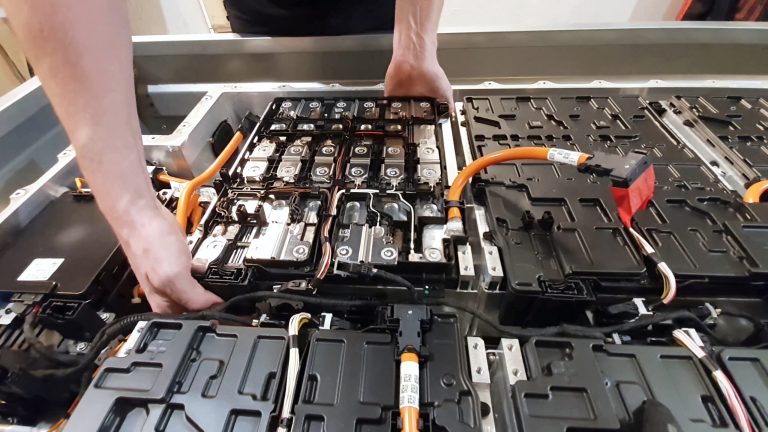 Technician handling an electric vehicle battery pack during inspection and maintenance