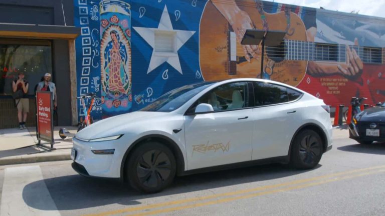 Tesla Robotaxi driving past a vibrant Austin mural, showcasing its autonomous ride-hailing service