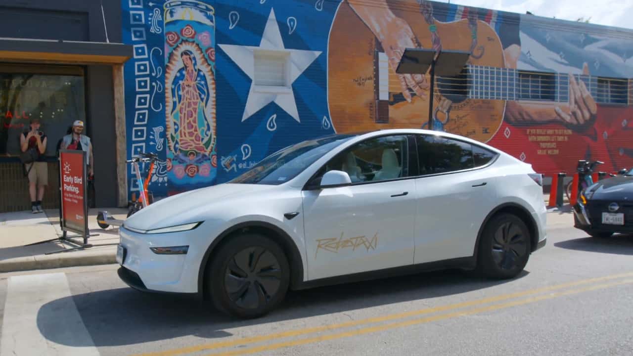 Tesla Robotaxi driving past a vibrant Austin mural, showcasing its autonomous ride-hailing service