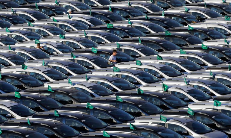 Thousands of GM vehicles sit tightly packed in storage lots, awaiting parts and final assembly