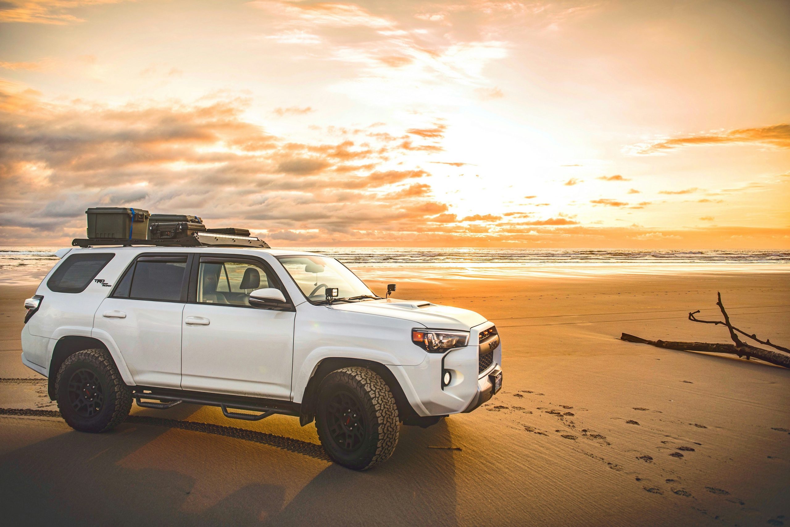 A Toyota is cruising on a beach on a sunny day