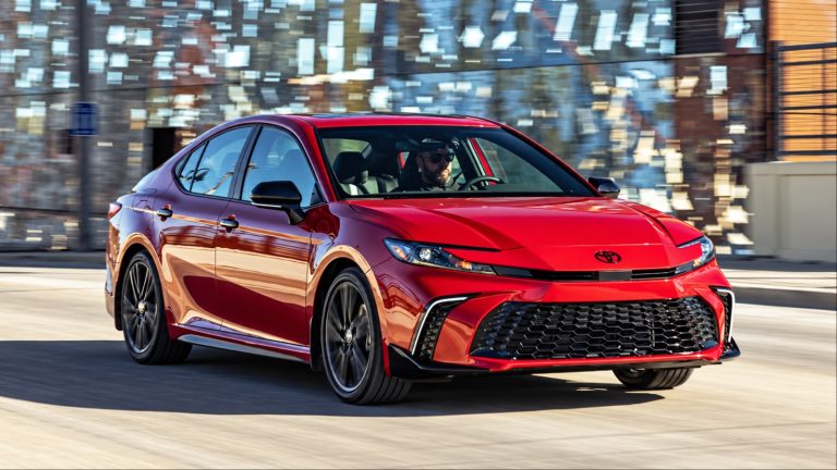 Red Toyota Camry driving on city street with male driver