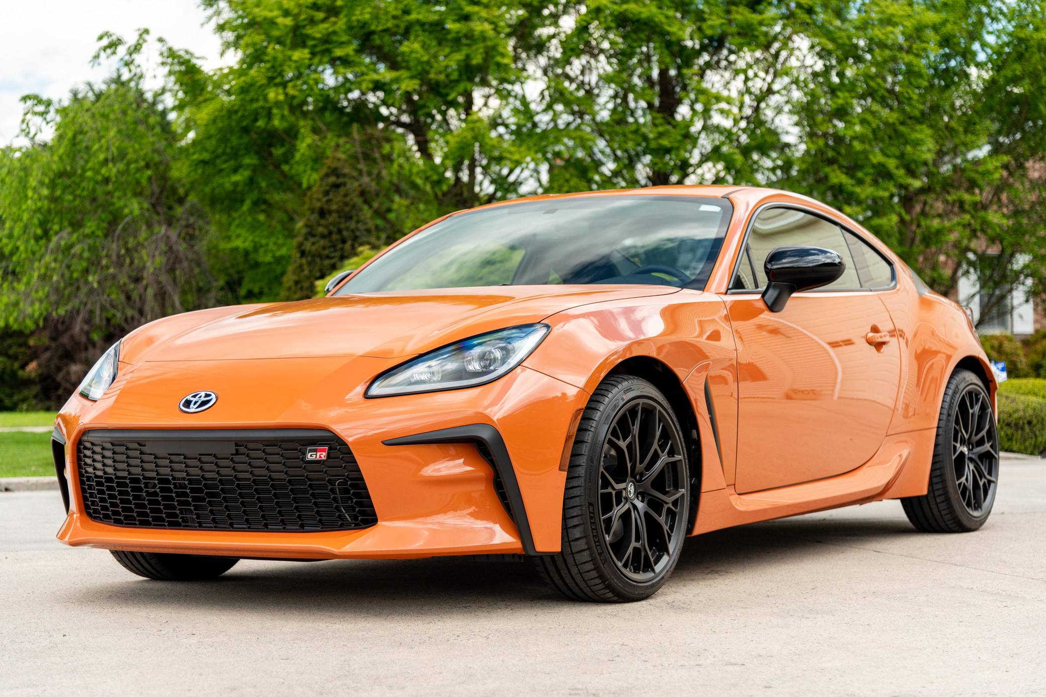 Toyota GR86 parked on a driveway, showcasing its aggressive front fascia and sporty coupe proportions