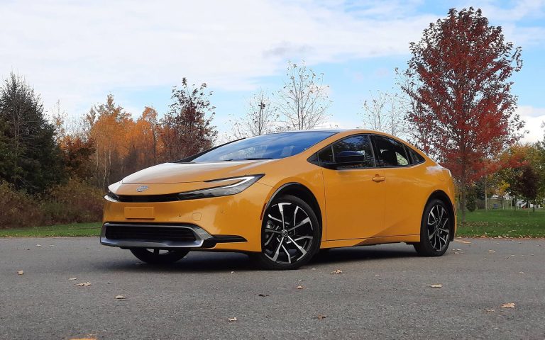 Toyota Prius Prime parked on a quiet road, framed by colorful autumn trees