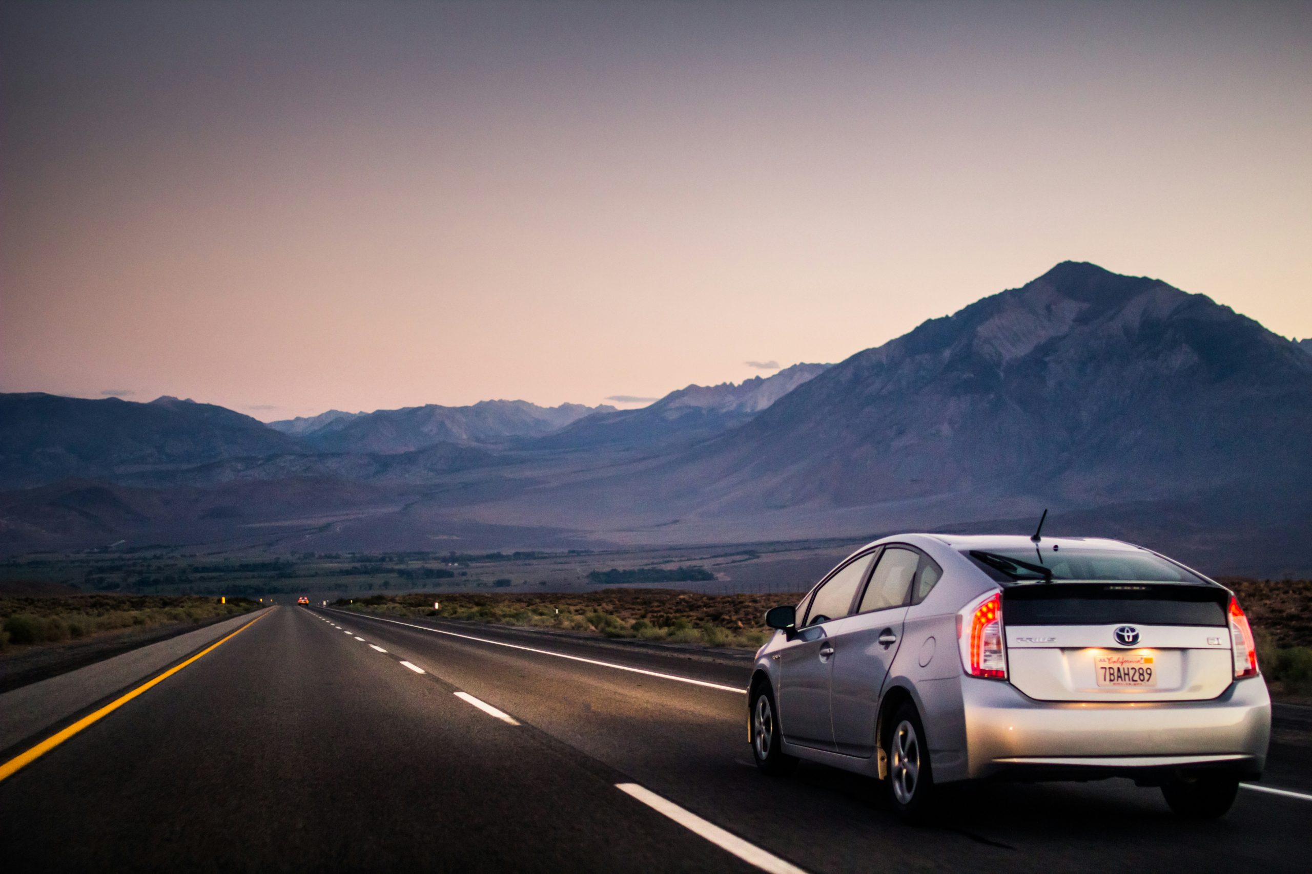 A Prius is driving on a highway at an evening