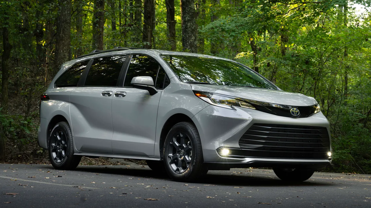 Silver Toyota Sienna Hybrid minivan parked on road in forest