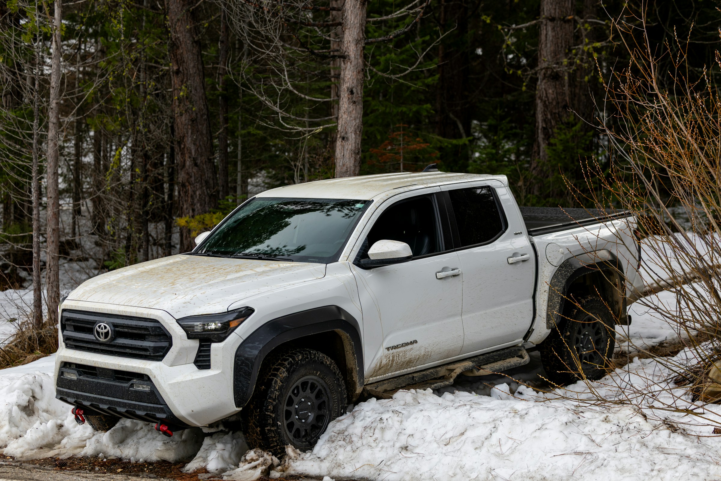 A Toyota Tacoma is cruising on ahilly route surrounded with snow