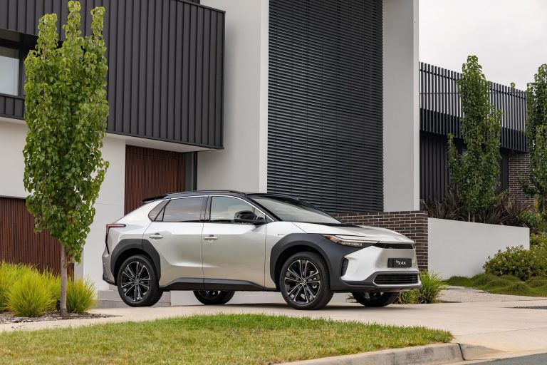 Toyota bZ4X electric SUV parked outside a modern home, showcasing its sleek exterior design